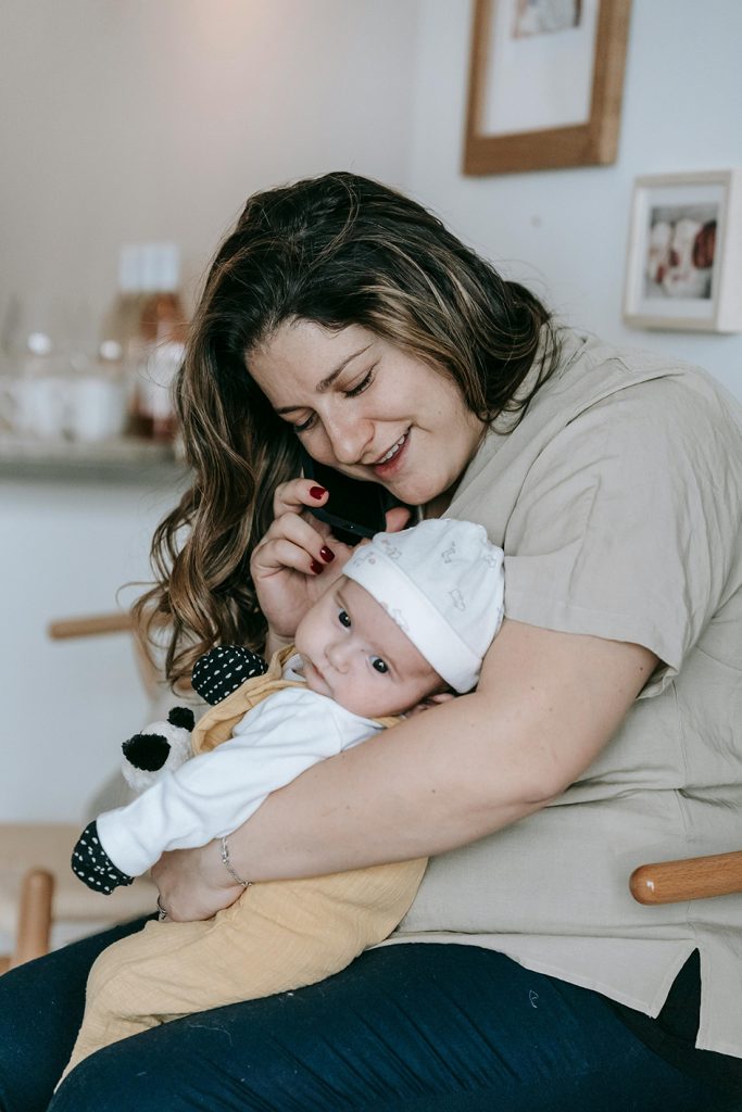 parent on the phone smiling and holding baby